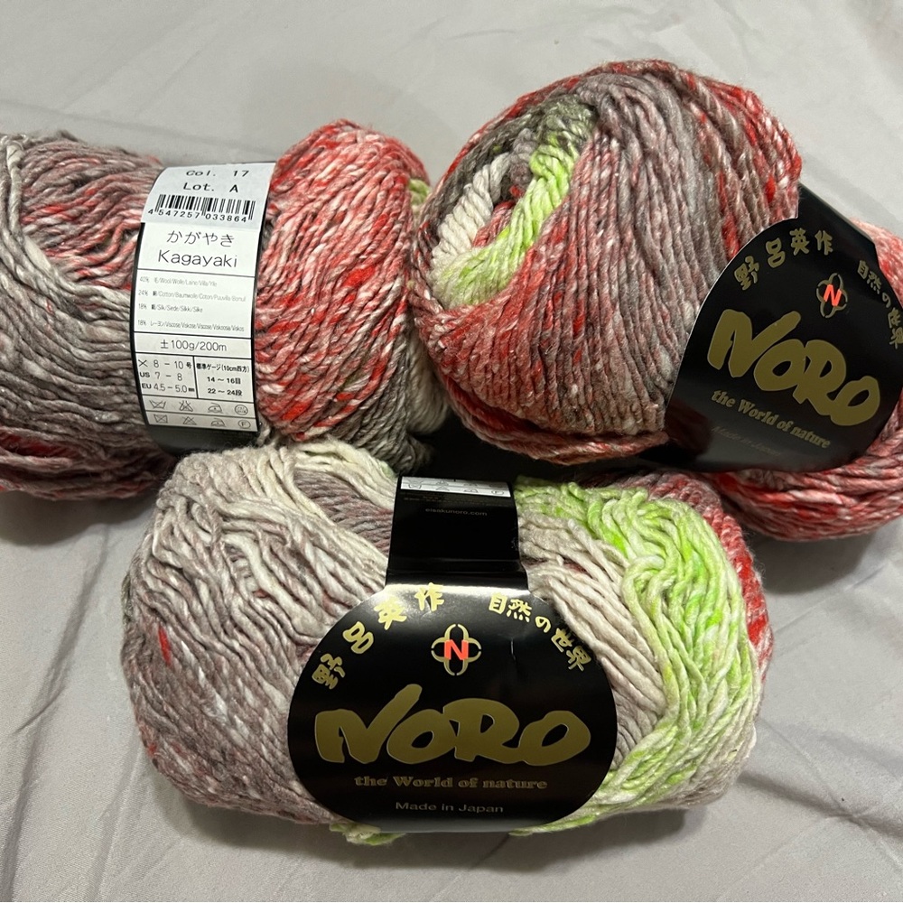 3 Skeins of Noro Kagayaki Yarn in colours Red, Neon Green, and Gray tones.